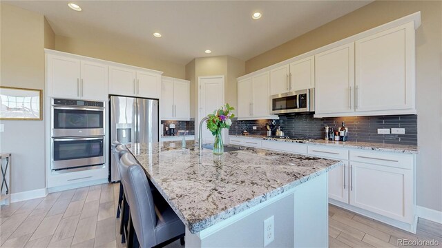 kitchen with white cabinetry, appliances with stainless steel finishes, and a kitchen island with sink