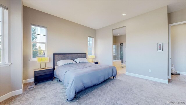 bedroom with ensuite bath and light colored carpet