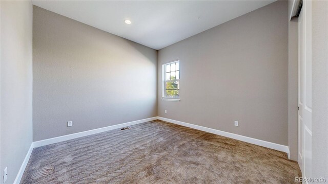 carpeted spare room featuring vaulted ceiling