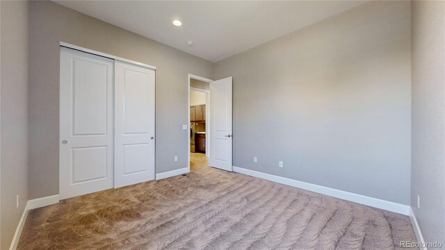 unfurnished bedroom featuring light carpet and a closet