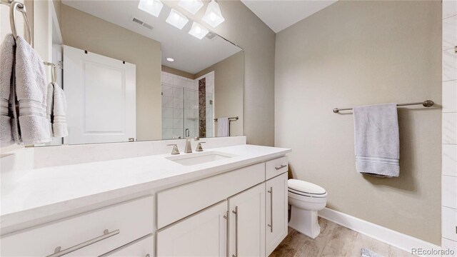 bathroom featuring walk in shower, wood-type flooring, vanity, and toilet