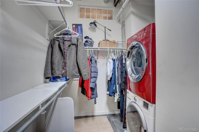 laundry room with laundry area, stacked washing maching and dryer, baseboards, and wood finished floors