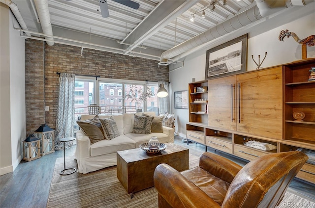 living area featuring a ceiling fan, rail lighting, brick wall, and wood finished floors