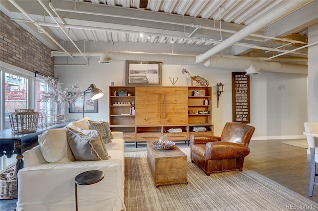 living room with brick wall, baseboards, and wood finished floors