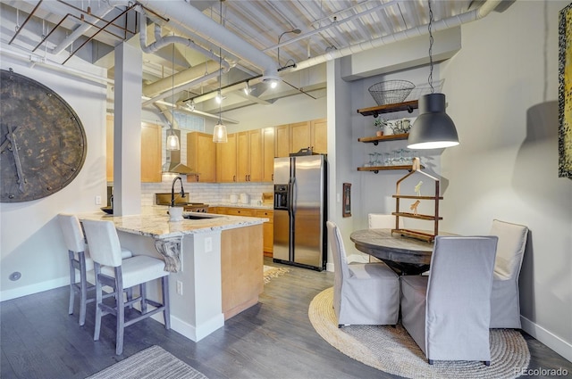 kitchen with stainless steel fridge, tasteful backsplash, wood finished floors, a peninsula, and a high ceiling