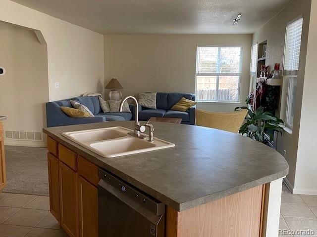 kitchen featuring an island with sink, stainless steel dishwasher, sink, and light tile patterned floors