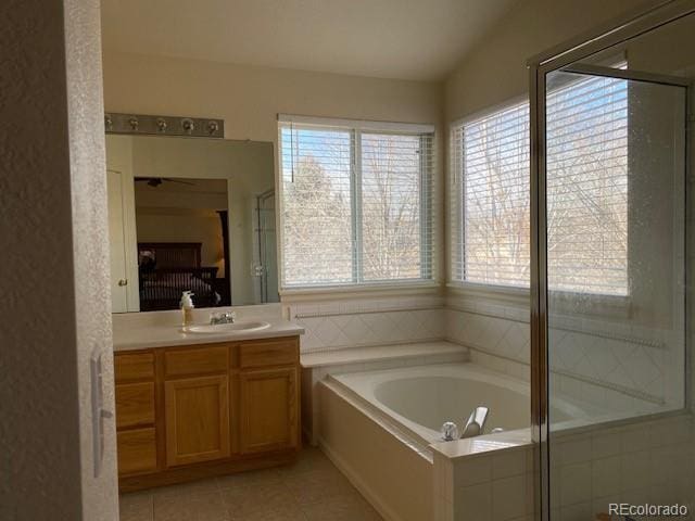 bathroom with tile patterned floors, lofted ceiling, a wealth of natural light, and vanity