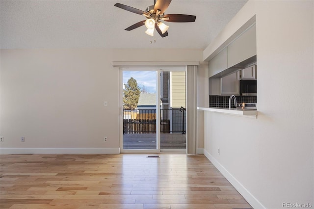 empty room with ceiling fan, sink, light hardwood / wood-style flooring, and a textured ceiling