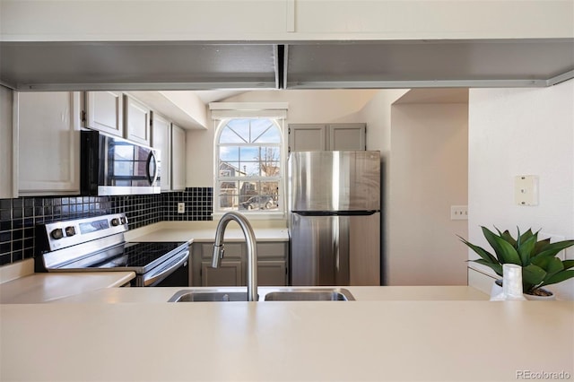 kitchen featuring stainless steel appliances, gray cabinets, sink, and decorative backsplash