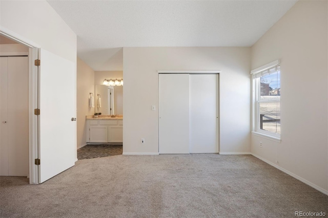 unfurnished bedroom featuring light colored carpet and ensuite bathroom