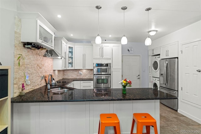 2511 S Bahama Cir Unit A, Aurora, CO 80013 - kitchen with appliances with stainless steel finishes, estacked washer and dryer, a peninsula, decorative backsplash, and white cabinetry