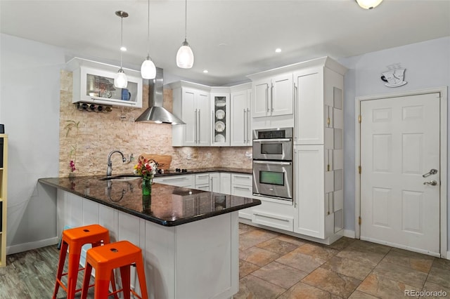 2511 S Bahama Cir Unit A, Aurora, CO 80013 - kitchen featuring wall chimney range hood, stainless steel double oven, glass insert cabinets, tasteful backsplash, and white cabinets