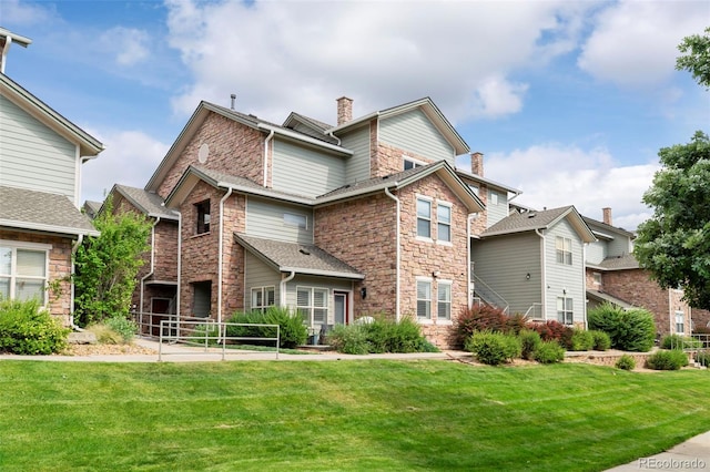 2511 S Bahama Cir Unit A, Aurora, CO 80013 - back of house featuring a chimney, stone siding, and a lawn