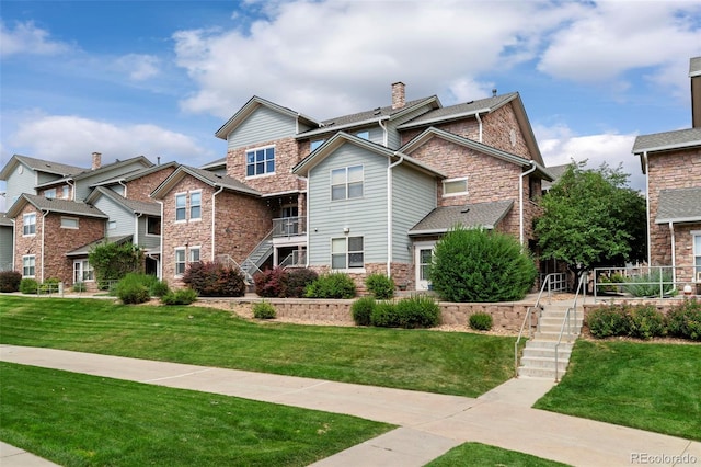 2511 S Bahama Cir Unit A, Aurora, CO 80013 - view of front facade with stairs, stone siding, a chimney, and a front lawn