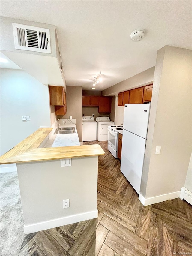 64 Nome Way Unit C, Aurora, CO 80012 - kitchen with white appliances, washer and clothes dryer, a peninsula, a sink, and brown cabinetry