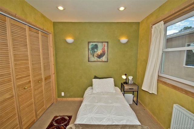 bedroom featuring radiator, light colored carpet, and a closet