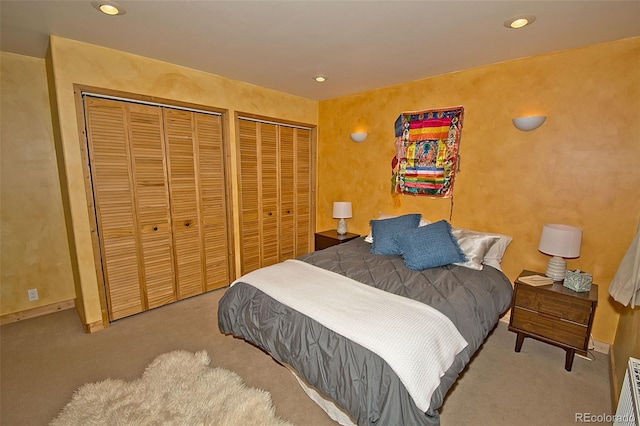 bedroom with multiple closets and light carpet