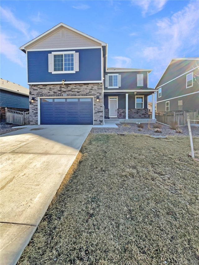 view of front of property featuring driveway, stone siding, a garage, and covered porch