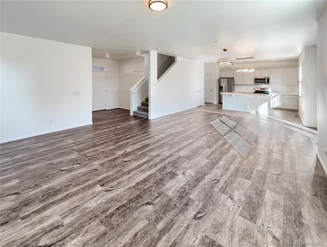 unfurnished living room with stairs, a sink, and light wood-style flooring