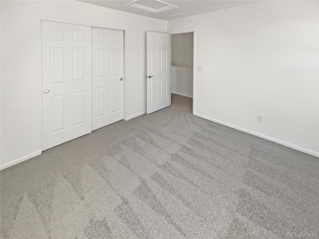 unfurnished bedroom featuring carpet floors, attic access, baseboards, and a closet