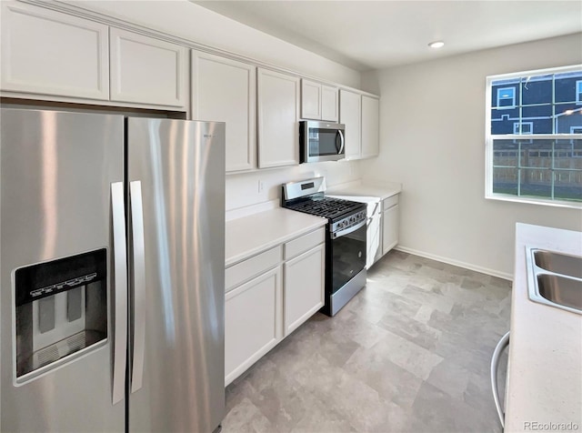 kitchen featuring light countertops, appliances with stainless steel finishes, white cabinets, and baseboards