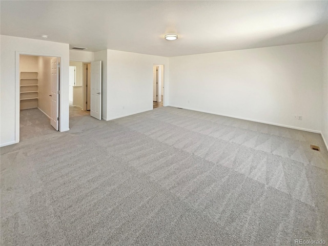 spare room featuring carpet, visible vents, and baseboards