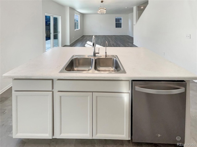 kitchen featuring open floor plan, stainless steel dishwasher, a sink, and white cabinets