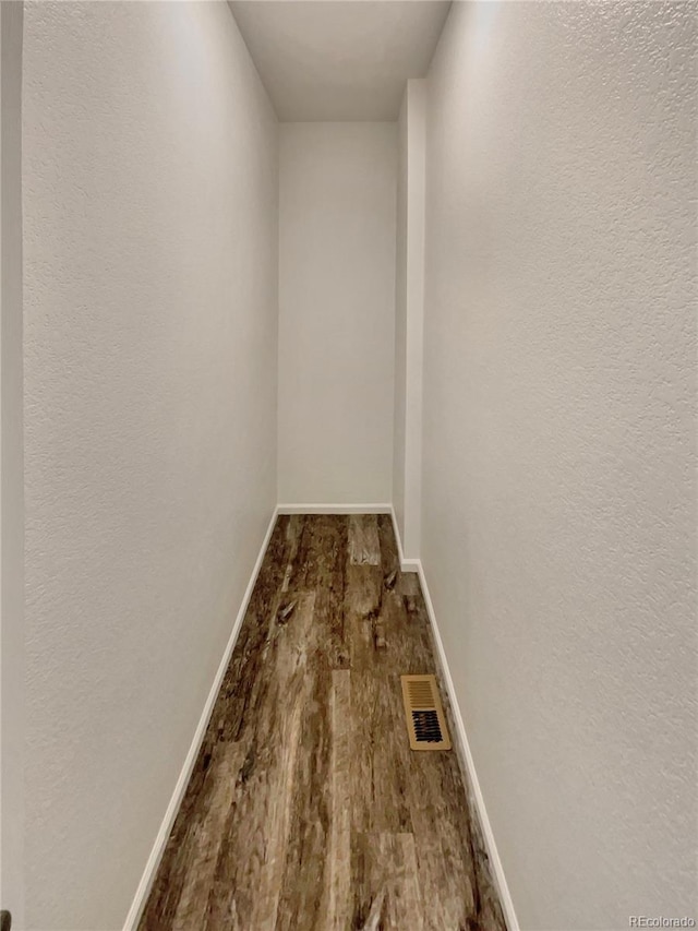 corridor featuring wood finished floors, visible vents, and baseboards