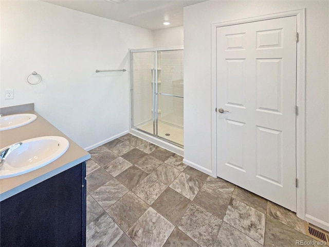 full bath featuring a stall shower, a sink, and baseboards