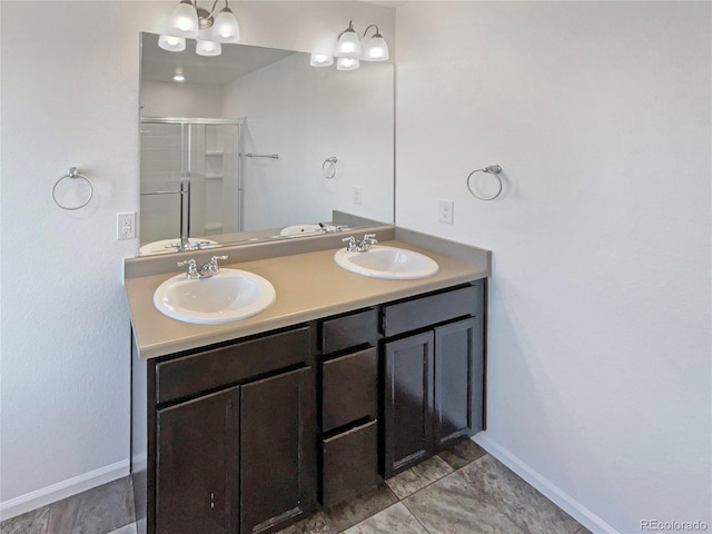 bathroom featuring double vanity, a shower stall, baseboards, and a sink