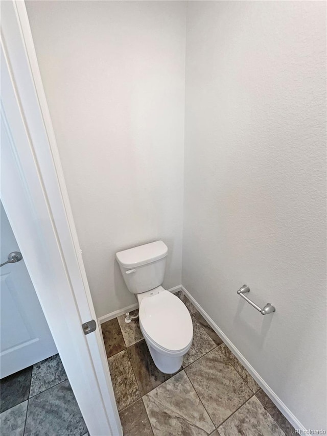 bathroom with toilet and baseboards