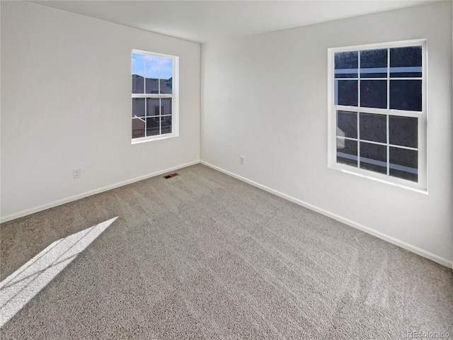 carpeted spare room featuring visible vents and baseboards