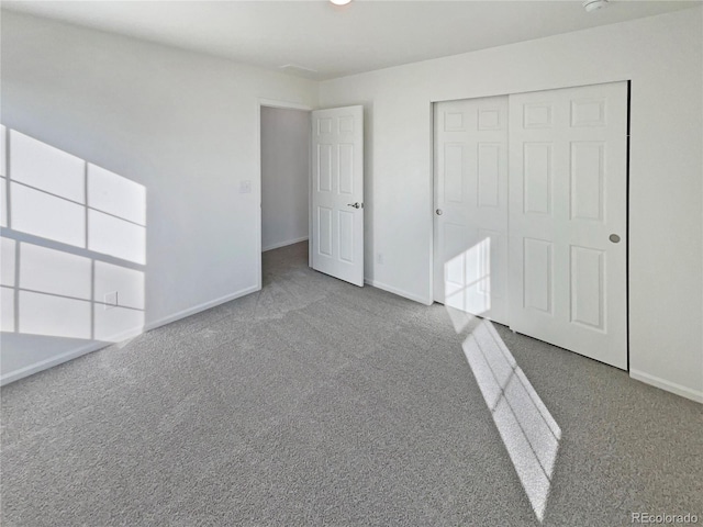 unfurnished bedroom featuring carpet floors, baseboards, and a closet