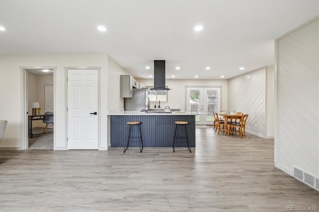 7952 Zuni St, Denver, CO 80221 - kitchen with island range hood, a breakfast bar area, freestanding refrigerator, light wood-type flooring, and a peninsula