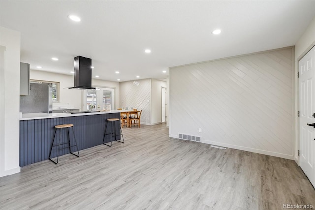 7952 Zuni St, Denver, CO 80221 - kitchen with freestanding refrigerator, island exhaust hood, light wood-style flooring, a kitchen bar, and a peninsula