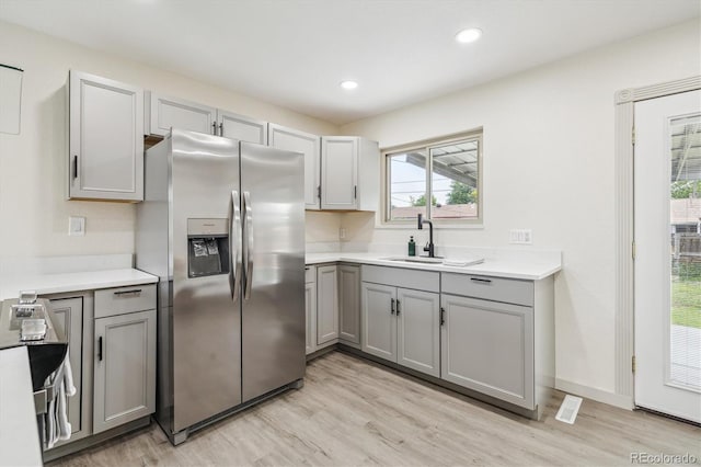 7952 Zuni St, Denver, CO 80221 - kitchen with stainless steel fridge, gray cabinetry, a sink, light wood-type flooring, and light countertops