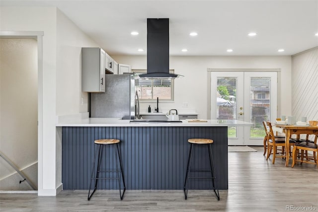 7952 Zuni St, Denver, CO 80221 - kitchen featuring island range hood, a peninsula, a breakfast bar area, light wood-style floors, and recessed lighting