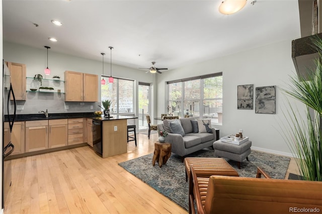 living area with recessed lighting, ceiling fan, light wood-style flooring, and baseboards