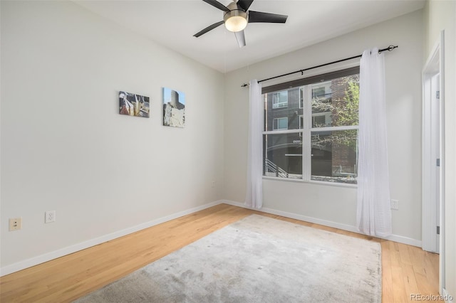 empty room with a ceiling fan, baseboards, and wood finished floors