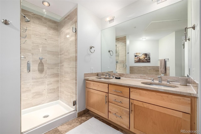 bathroom featuring double vanity, a stall shower, and a sink