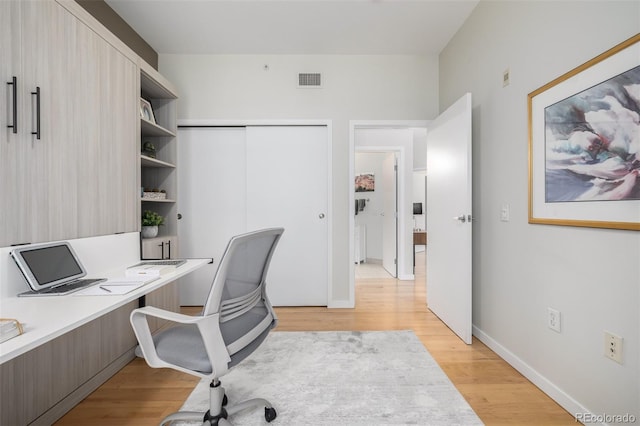 home office featuring visible vents, light wood-style flooring, and baseboards