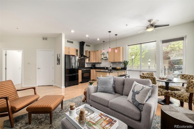 living room with ceiling fan, sink, and light wood-type flooring