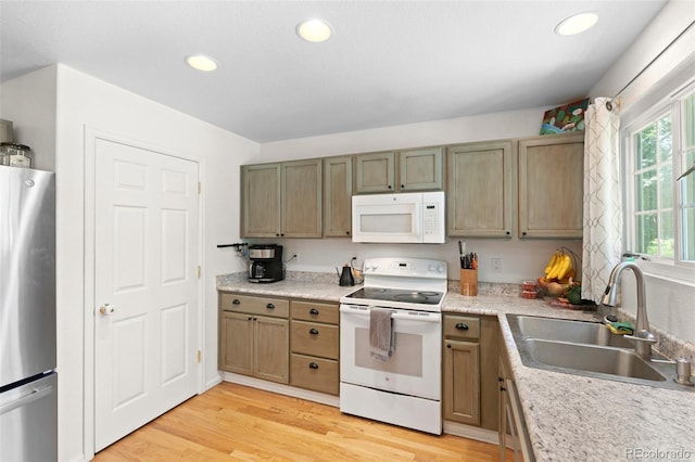 kitchen featuring light wood-type flooring, white appliances, a wealth of natural light, and sink