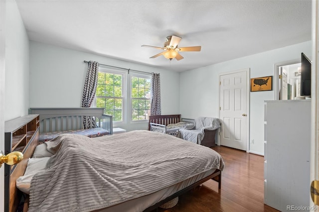 bedroom featuring ceiling fan, dark hardwood / wood-style floors, and a textured ceiling