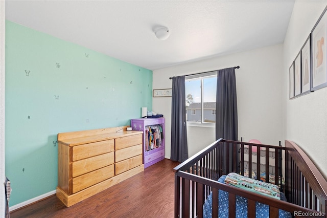 bedroom with a crib and dark hardwood / wood-style floors