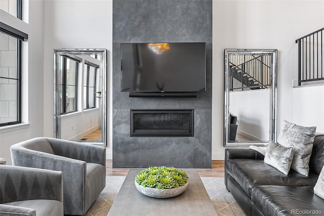 living area with wood finished floors, plenty of natural light, a fireplace, and baseboards