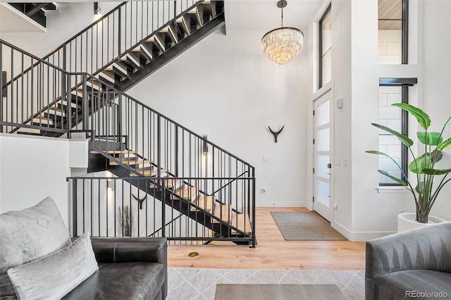 entrance foyer with a towering ceiling, a notable chandelier, baseboards, and wood finished floors