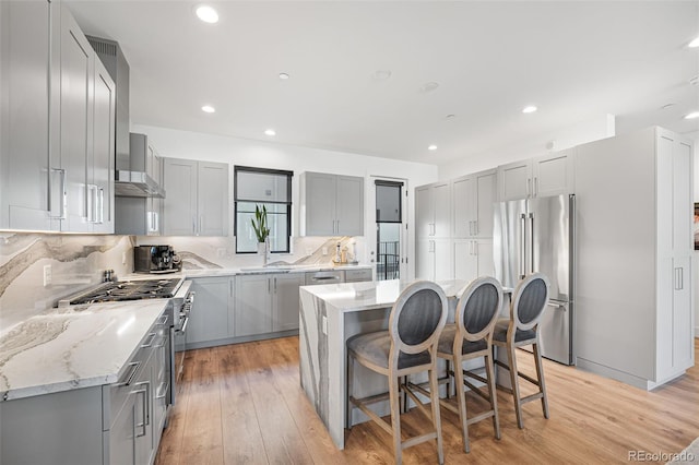 kitchen featuring high quality appliances, light stone counters, backsplash, and gray cabinetry