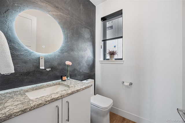 bathroom featuring baseboards, vanity, toilet, and wood finished floors