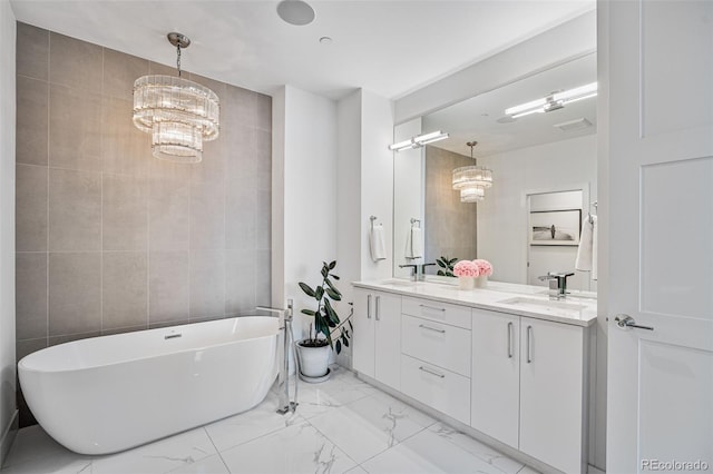 bathroom with a freestanding bath, marble finish floor, a sink, and tile walls